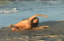 Naked girl doing yoga on the beach